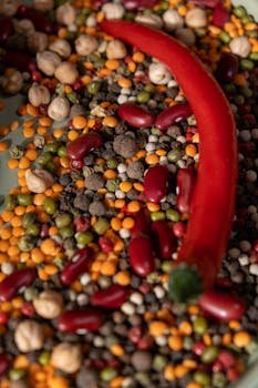 Colorful close-up of raw spices and legumes with a vibrant red chili pepper.